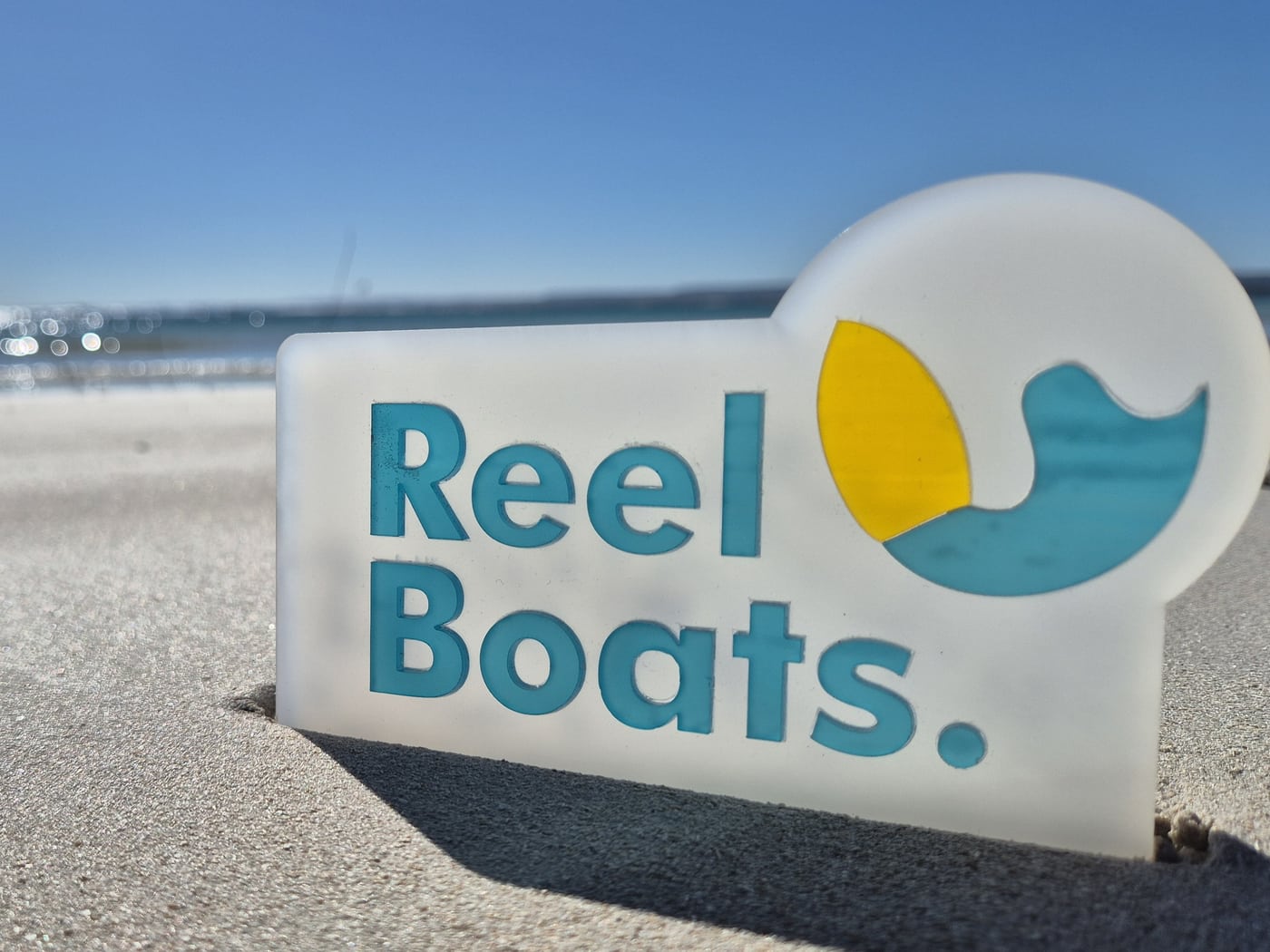 Reel Boats sign standing in the sand at a Geraldton beach