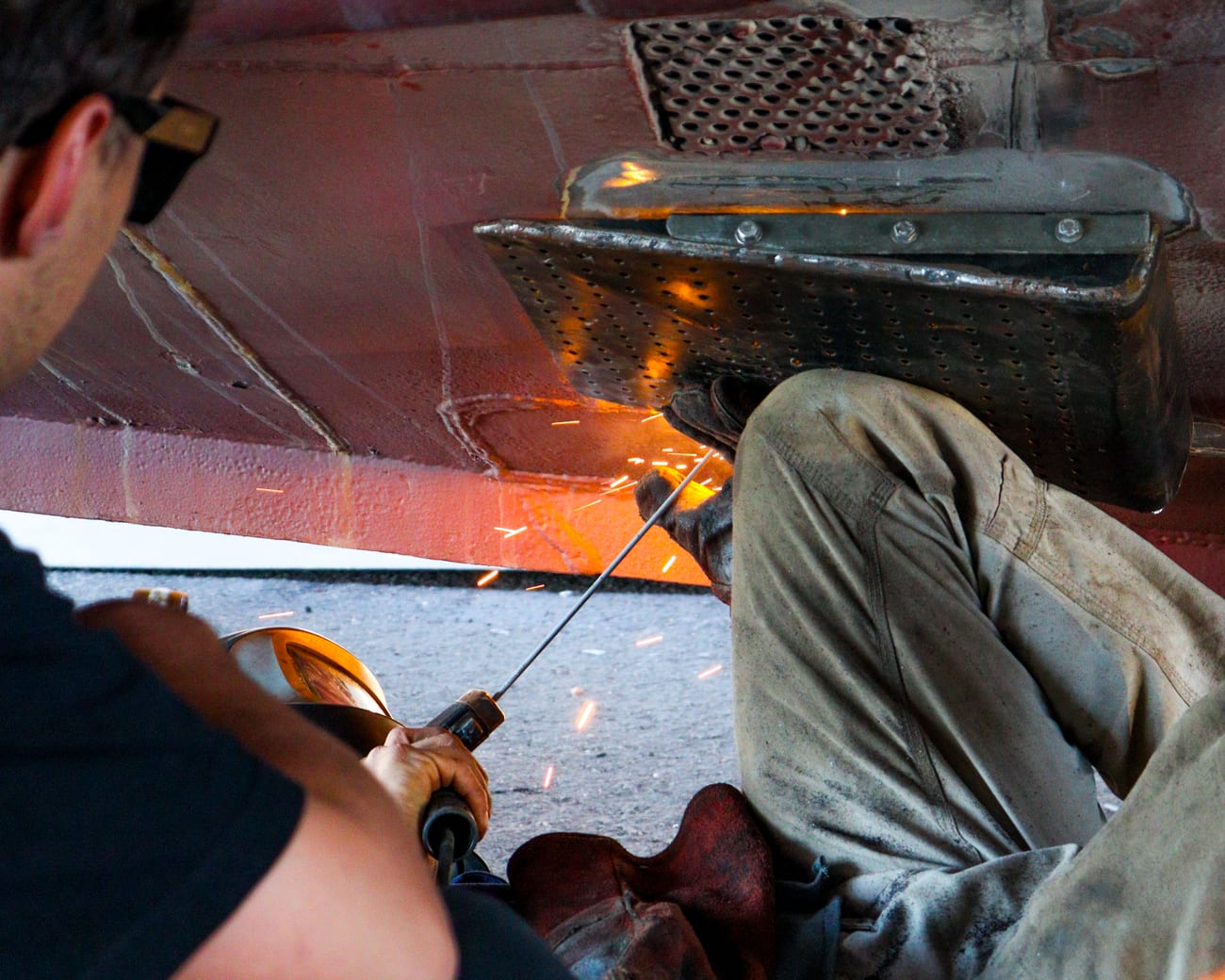 Welding a repair under a boat hull in the Reel Boats workshop